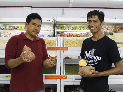 Leader supermarket manager, Teofilho da Silva (left) and World Vision's economic development specialist, Jesuinho Gusmão show local produce from Bobonaro farmers. Photo: Seung Eun Lim/World Vision